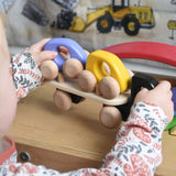 A child playing with a black coloured Bajo Auto Transporter. The wooden toy car transporter comes with two cars, one purple and one yellow. These heirloom quality toys by Bajo are part of a wide range of wooden toys available here at Babipur. 