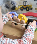A child playing with a black coloured Bajo Auto Transporter. The wooden toy car transporter comes with two cars, one purple and one yellow. These heirloom quality toys by Bajo are part of a wide range of wooden toys available here at Babipur. 