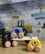 A black coloured Bajo Auto Transporter. The wooden toy car transporter comes with two cars, one purple and one yellow. These heirloom quality toys by Bajo are part of a wide range of wooden toys available here at Babipur. 