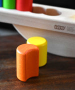 A close up of the orange moon shaped block from the Bajo Balance Scale wooden toy. A wooden base with a curved base with coloured wooden blocks that sit on top. These heirloom quality toys by Bajo are part of a wide range of wooden toys available here at Babipur.
