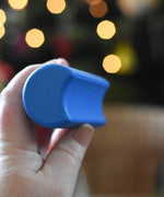 A close up of a blue moon shaped block from the Bajo Balance Scale wooden toy. A wooden base with a curved base with coloured wooden blocks that sit on top. These heirloom quality toys by Bajo are part of a wide range of wooden toys available here at Babipur.