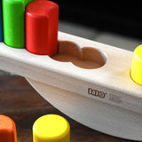 A close up of the circular shaped slots in the base of the Bajo Balance Scale wooden toy. A wooden base with a curved base with coloured wooden blocks that sit on top. These heirloom quality toys by Bajo are part of a wide range of wooden toys available here at Babipur.
