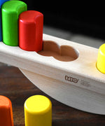 A close up of the circular shaped slots in the base of the Bajo Balance Scale wooden toy. A wooden base with a curved base with coloured wooden blocks that sit on top. These heirloom quality toys by Bajo are part of a wide range of wooden toys available here at Babipur.