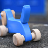 Close up of the blue wooden tail on the Bajo blue dachshund puppy placed on a stone wall outdoors. 