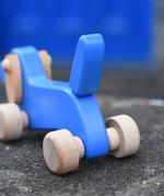 Close up of the blue wooden tail on the Bajo blue dachshund puppy placed on a stone wall outdoors. 