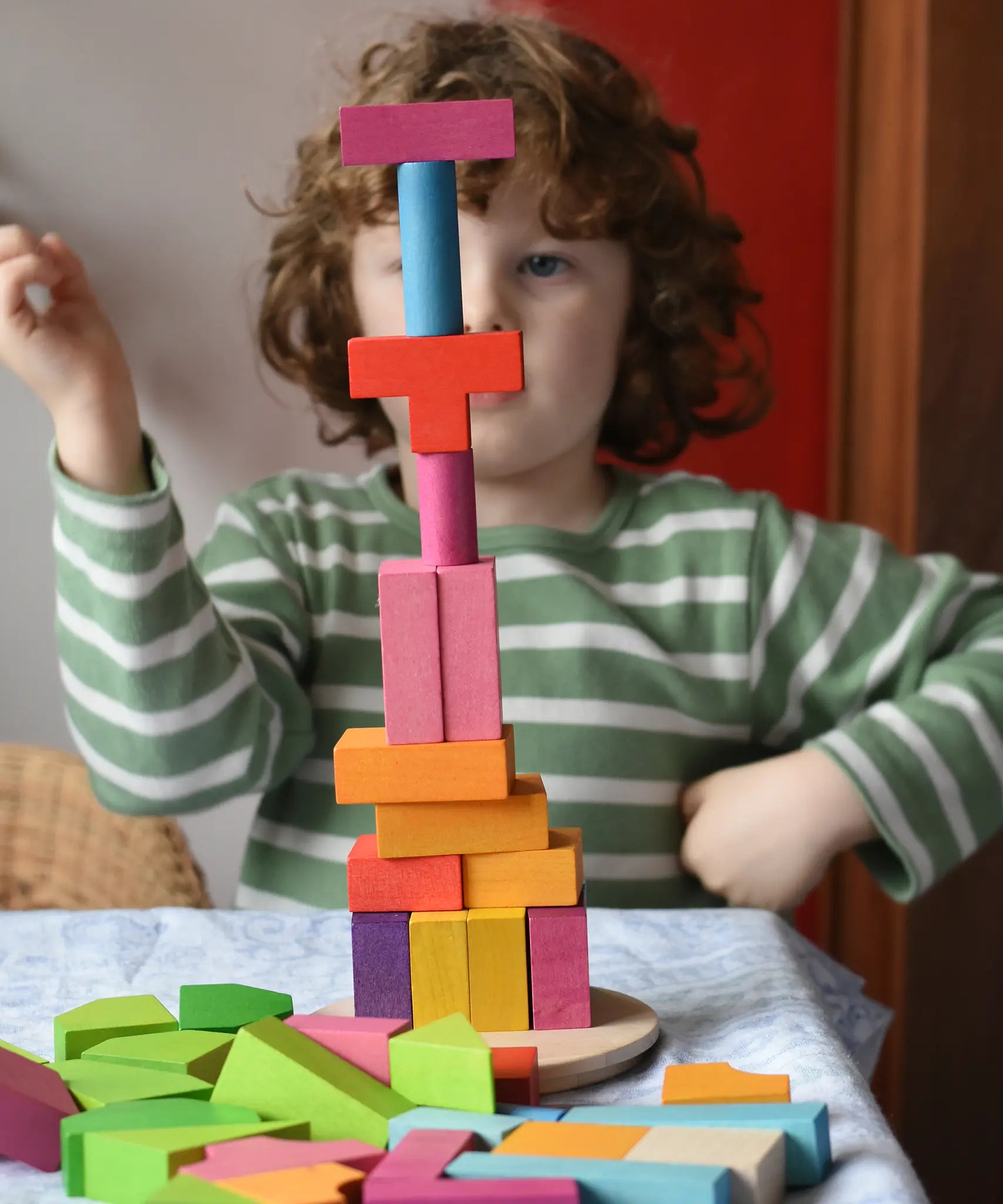 Bajo 43 wooden building blocks. Child stacking blocks on wooden lid of box into a high tower.