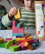 Bajo 43 wooden building blocks. 43 blocks, in 16 different shapes and 10 colours. Child stacking blocks on wooden lid of box.