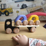 A child playing with a black coloured Bajo Auto Transporter. The wooden toy car transporter comes with two cars, one purple and one yellow. These heirloom quality toys by Bajo are part of a wide range of wooden toys available here at Babipur. 
