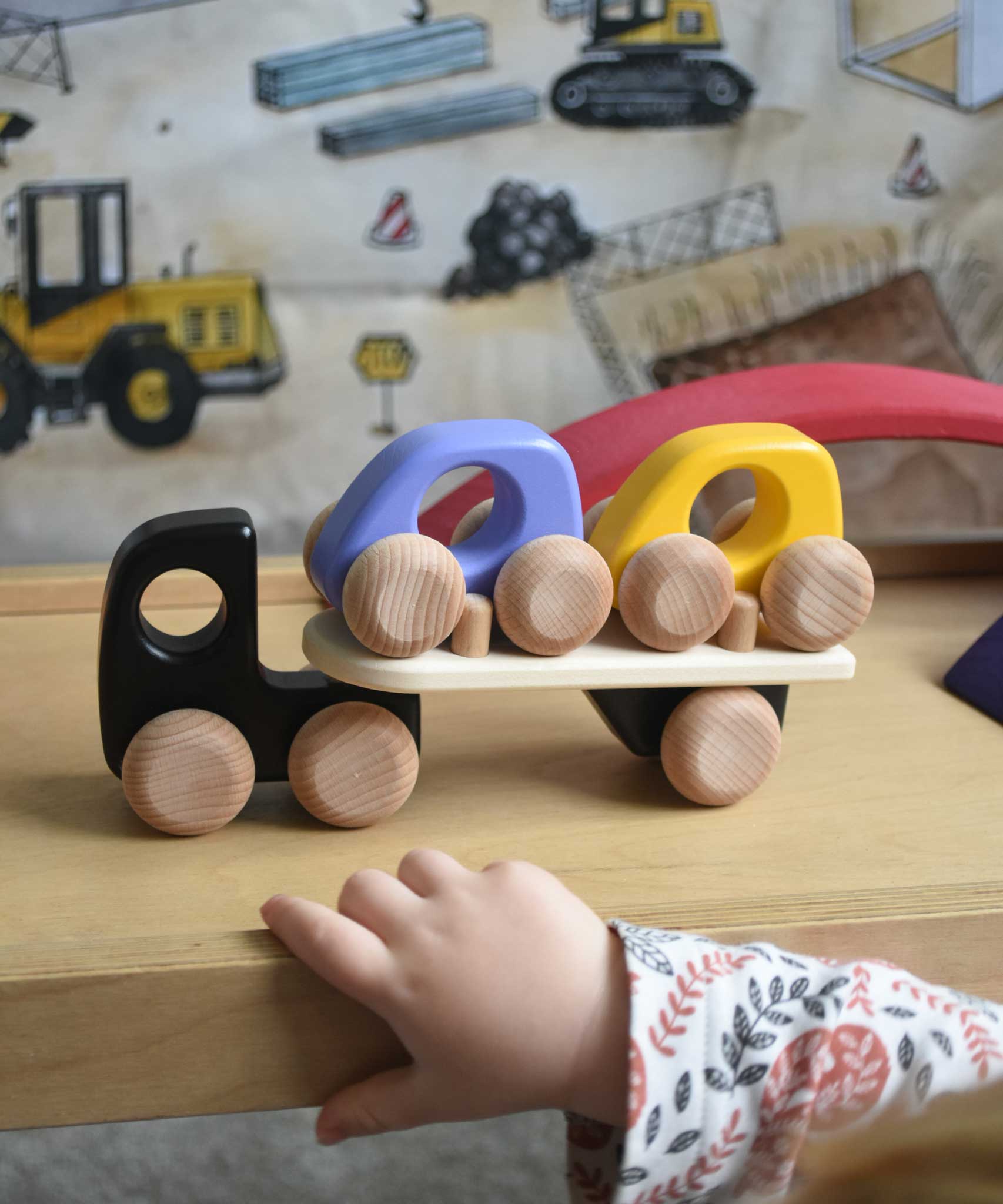 A child playing with a black coloured Bajo Auto Transporter. The wooden toy car transporter comes with two cars, one purple and one yellow. These heirloom quality toys by Bajo are part of a wide range of wooden toys available here at Babipur. 
