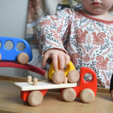 A child playing with a red coloured Bajo Auto Transporter. The wooden toy car transporter comes with two cars, one green and one blue. These heirloom quality toys by Bajo are part of a wide range of wooden toys available here at Babipur. 