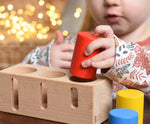 A child playing with the Bajo Deep And Shallow Sorter wooden toy placed on a small wooden table. These heirloom quality toys by Bajo are part of a wide range of wooden toys available here at Babipur. 