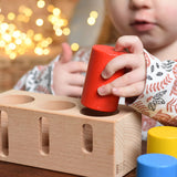 A child playing with the Bajo Deep And Shallow Sorter wooden toy placed on a small wooden table. These heirloom quality toys by Bajo are part of a wide range of wooden toys available here at Babipur. 