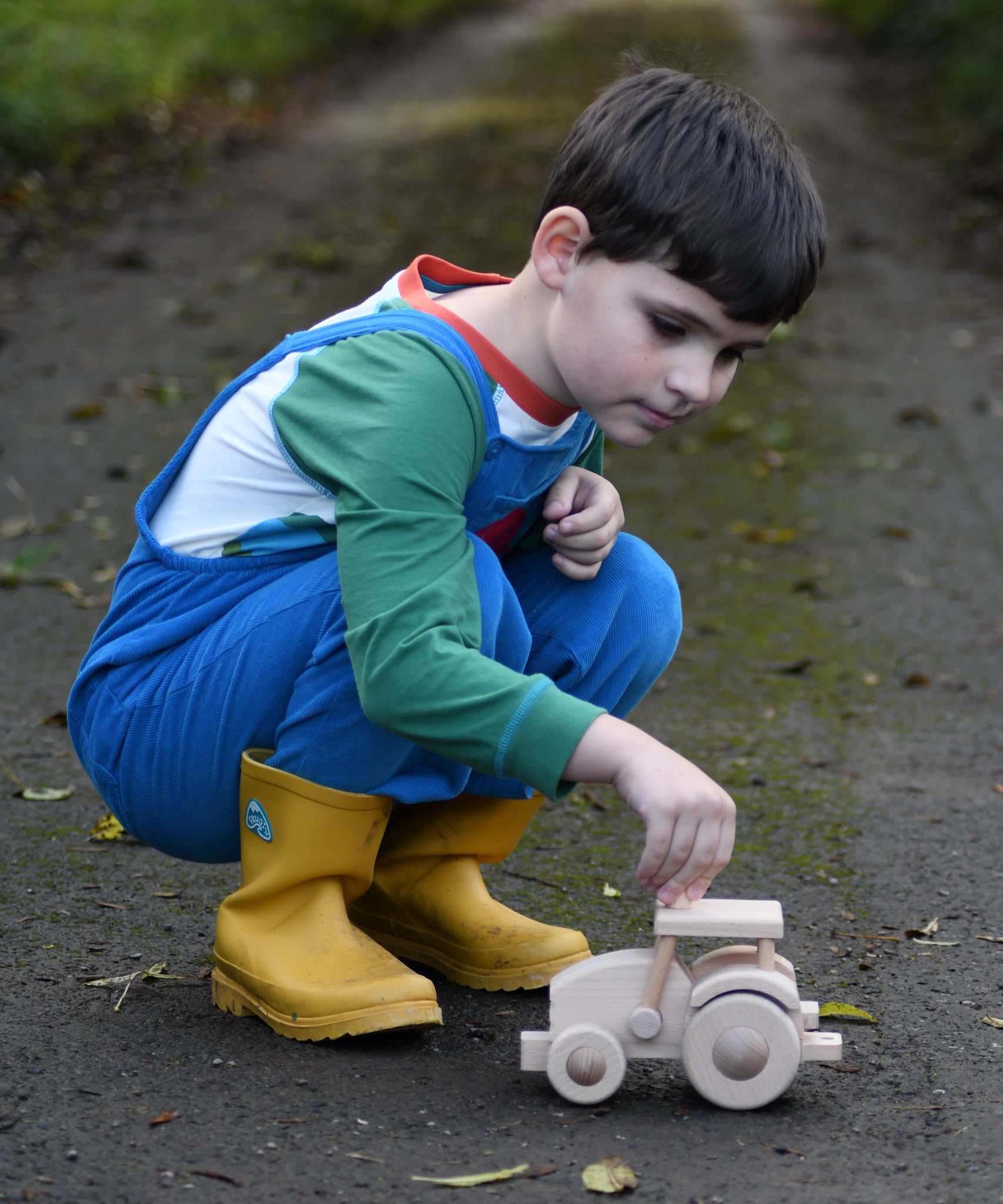 A child kneeling down next to wooden toy tractor made using the Bajo DIY tractor kit. These heirloom quality toys by Bajo are part of a wide range of wooden toys available here at Babipur. 
