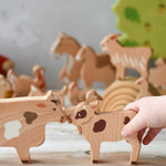 A child's hand holding the calf figure  from the Bajo farm animals set. Other animal figures can be seen in the background.