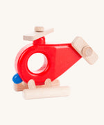 Bajo Red Fire Engine Helicopter wooden toy. The red coloured wooden helicopter has natural propellers and stand and a blue lamp details on the front. These heirloom quality toys by Bajo are part of a wide range of wooden toys available here at Babipur. 
