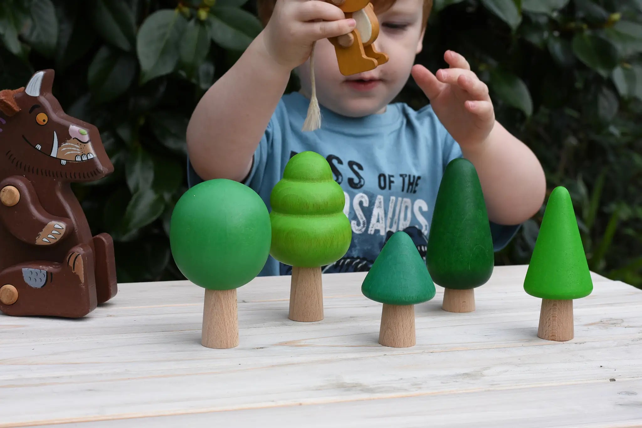 Child playing with the Gruffalo mouse figure in between the Bajo green forest tree set figures.