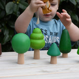 Child playing with the Gruffalo mouse figure in between the Bajo green forest tree set figures.