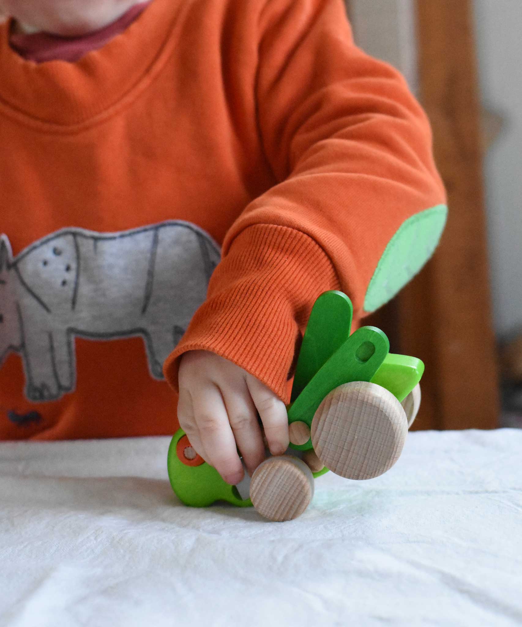 A child playing with the Bajo green Grasshopper wooden toy. These heirloom quality toys by Bajo are part of a wide range of wooden toys available here at Babipur.