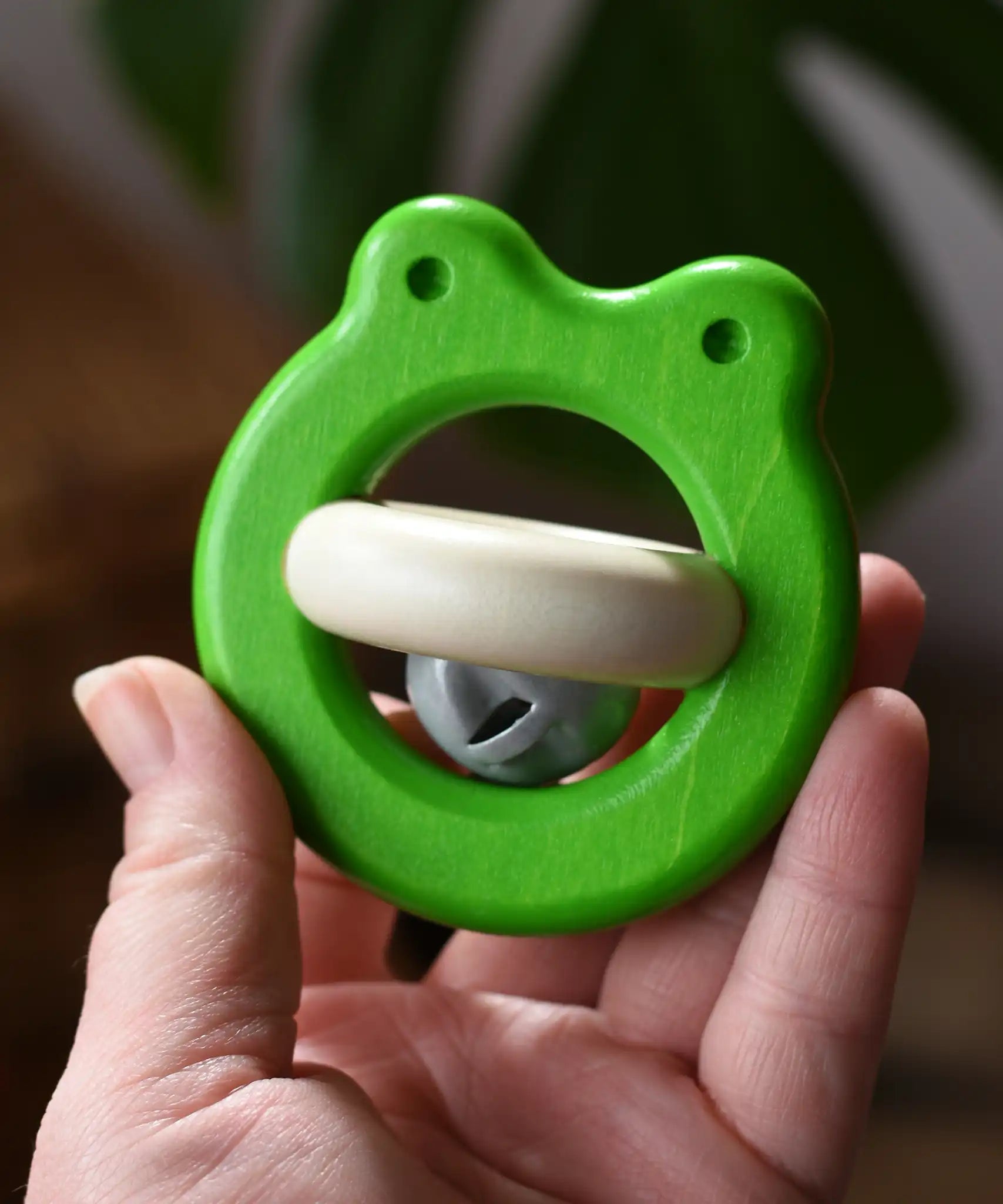 Bajo green Frog Rattle wooden baby toy in an adult's hand in the Babipur playroom