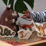 Bajo Gruffalo character puzzle pieces placed on a rattan stool next to a Bajo Gruffalo wooden figure.