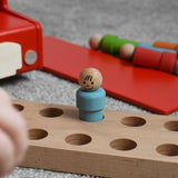 A close up of one of the blue peg dolls from the Bajo London bus wooden toy placed on the wooden floor base from the bus.  These heirloom quality toys by Bajo are part of a wide range of wooden toys available here at Babipur
