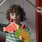 Bajo magnetic fishing game toy. Children holding wooden rodd with red and yellow fish attached.