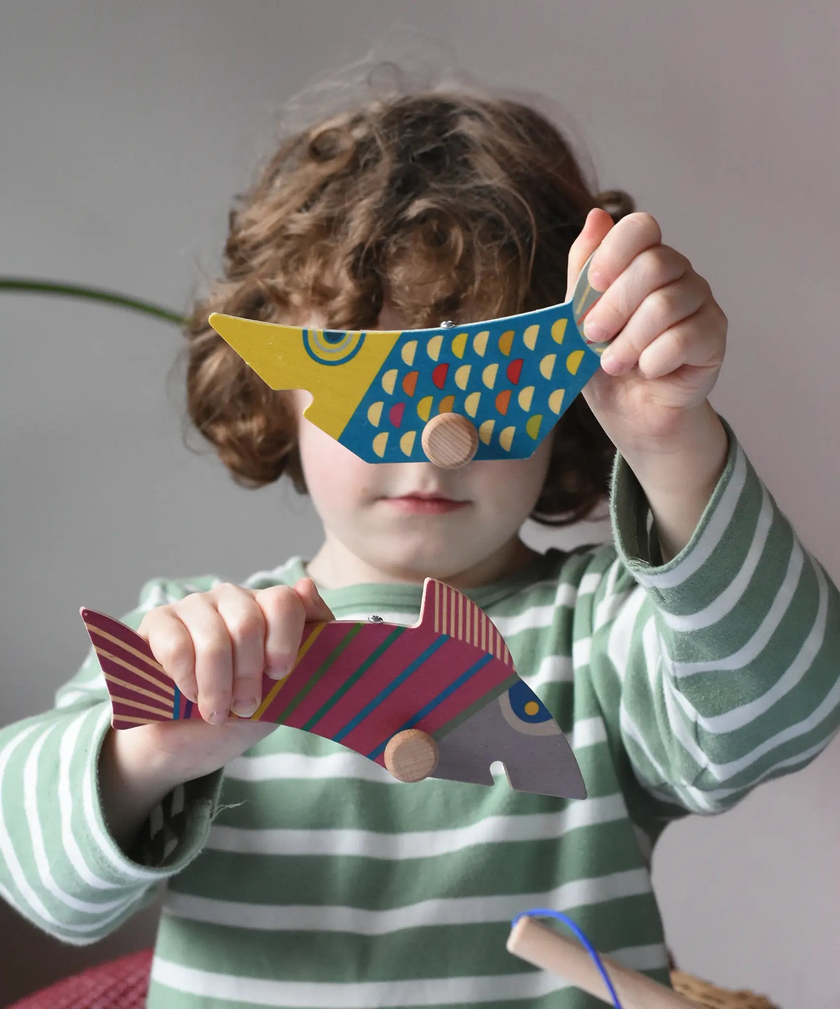 Bajo magnetic fishing game toy fish figure pieces in a child's hands.