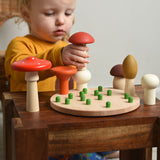 A child playing with the Bajo Wooden Mushroom Forest Peg Puzzle. The child is placing the red topped  mushroom on top of the white button mushroom. These heirloom quality toys by Bajo are part of a wide range of wooden toys available here at Babipur. 