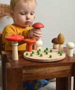 A child playing with the Bajo Wooden Mushroom Forest Peg Puzzle. The child is placing the red topped  mushroom on top of the white button mushroom. These heirloom quality toys by Bajo are part of a wide range of wooden toys available here at Babipur. 