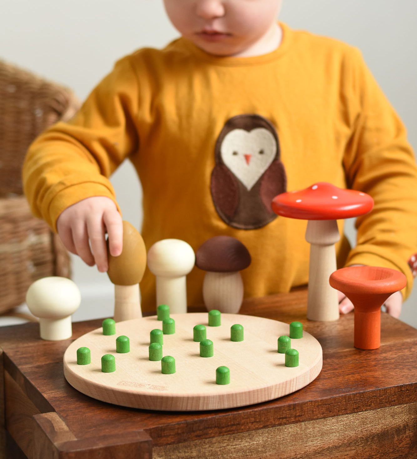 A child playing with the Bajo Wooden Mushroom Forest Peg Puzzle. The child is picking up the yellow coloured mushroom. These heirloom quality toys by Bajo are part of a wide range of wooden toys available here at Babipur. 