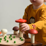 A child playing with the Bajo Wooden Mushroom Forest Peg Puzzle. The child is picking up the yellow coloured mushroom from the base. These heirloom quality toys by Bajo are part of a wide range of wooden toys available here at Babipur. 