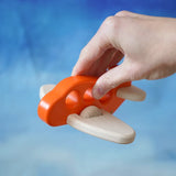 Adult hand holding a Bajo Toys wooden push along airplane in orange showing scale