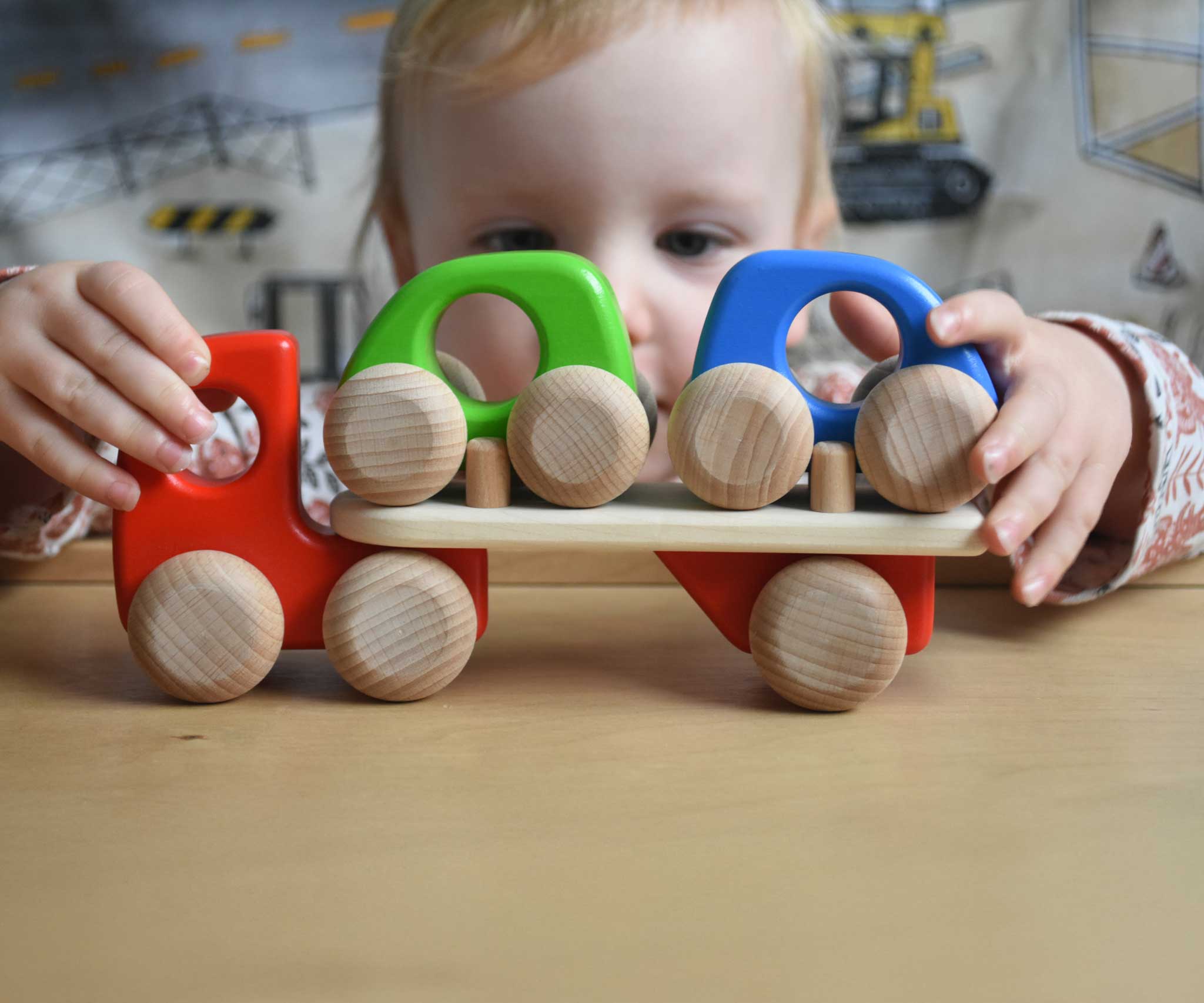 A child playing with a red coloured Bajo Auto Transporter. The wooden toy car transporter comes with two wooden toy cars. These heirloom quality toys by Bajo are part of a wide range of wooden toys available here at Babipur. 