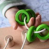 Bajo rope abacus toy with 10 pegs. Rope with green rings on in child's hand.