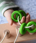 Bajo rope abacus toy with 10 pegs. Rope with green rings on in child's hand.