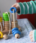 Bajo rope abacus toy with 10 pegs. Child lifting the wooden rings from the number 10 peg.