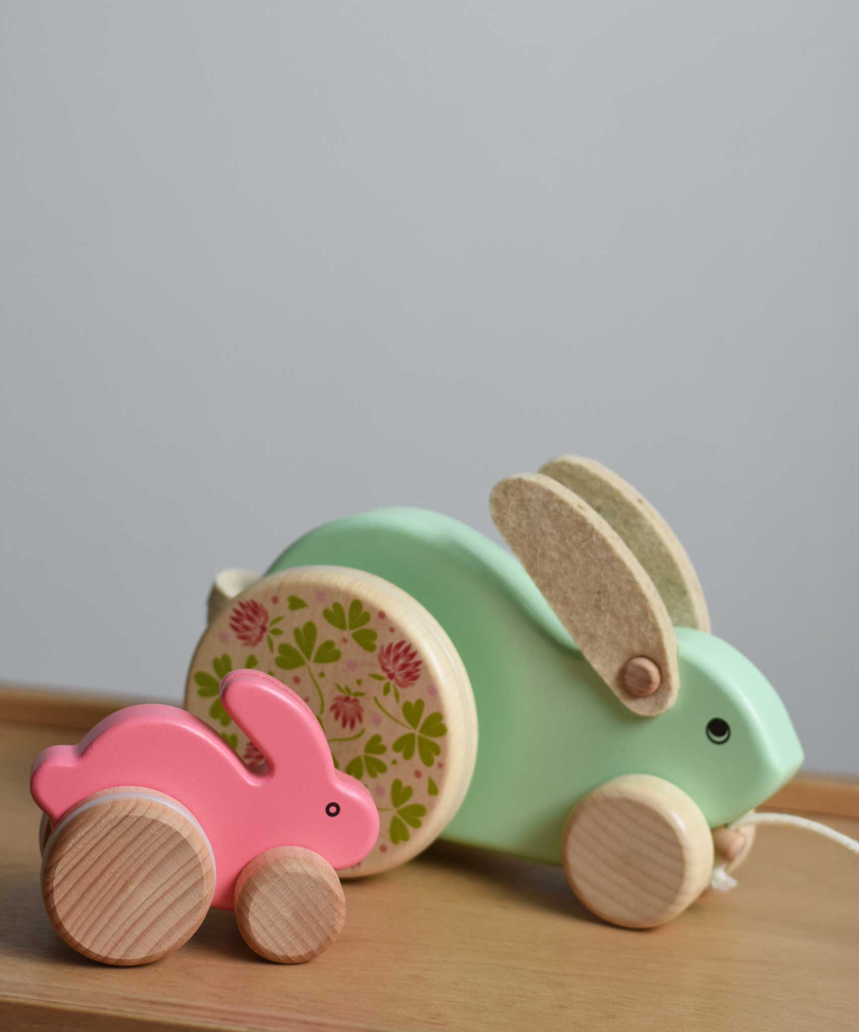 A pink coloured small and a large mint green Bajo rabbit placed next to each other on a Triclimb Miri slide  These heirloom quality toys by Bajo are part of a wide range of wooden toys available here at Babipur.