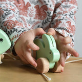 A close up of a mint green coloured small Bajo rabbit in a child's hands.  These heirloom quality toys by Bajo are part of a wide range of wooden toys available here at Babipur.