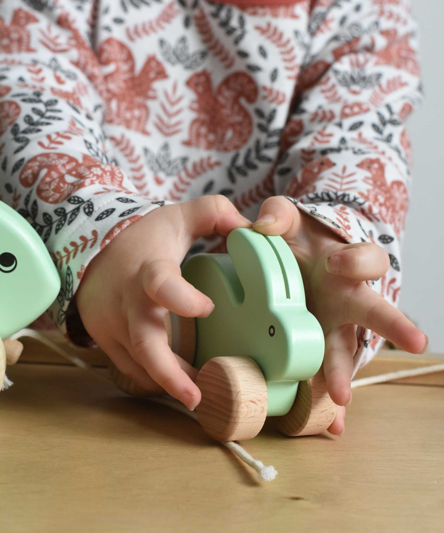 A close up of a mint green coloured small Bajo rabbit in a child's hands.  These heirloom quality toys by Bajo are part of a wide range of wooden toys available here at Babipur.