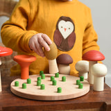 A child playing with the Bajo Wooden Mushroom Forest Peg Puzzle. The child is placing the yellow coloured mushroom on one of the green coloured pegs on the wooden base. These heirloom quality toys by Bajo are part of a wide range of wooden toys available here at Babipur. 