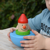 Child holding the Bajo roly poly wobbling dwarf wooden baby toy.