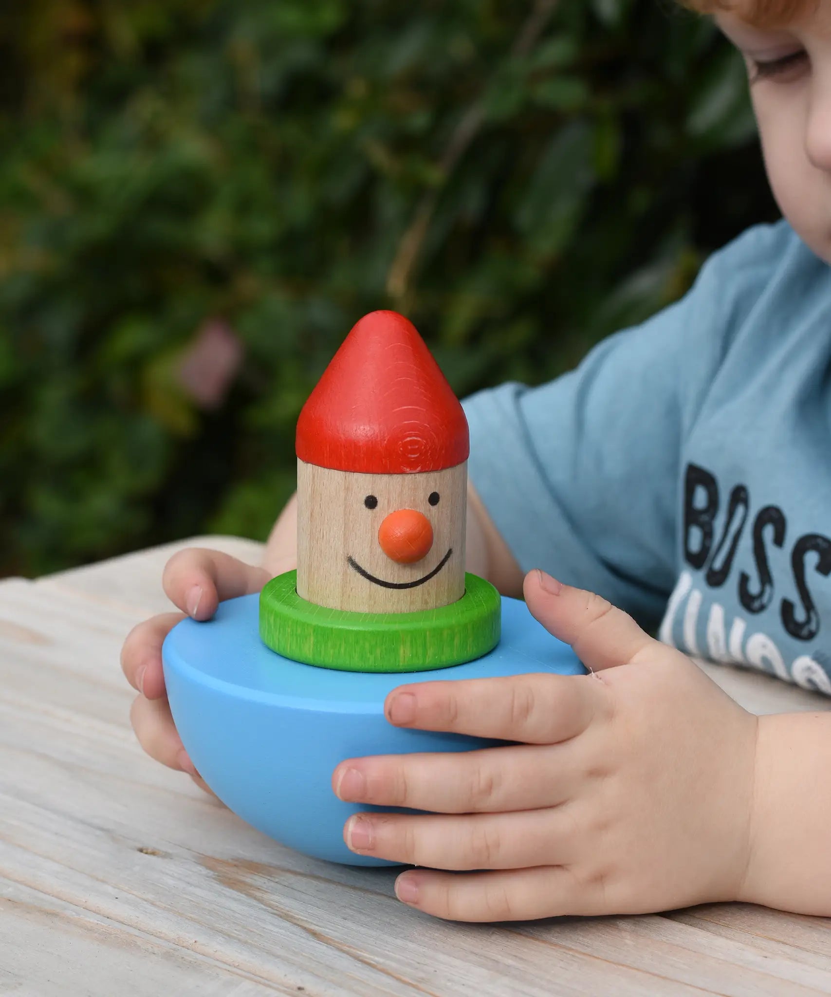 Child holding the Bajo roly poly wobbling dwarf wooden baby toy.