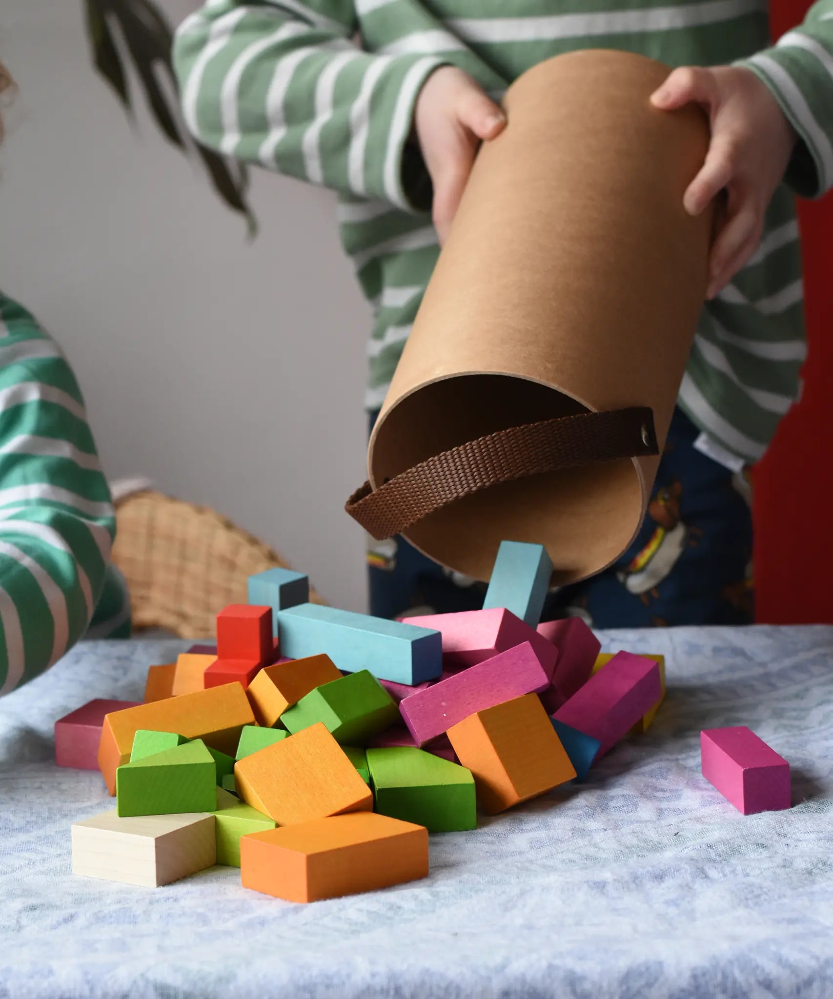 Bajo 43 wooden building blocks. 43 blocks, in 16 different shapes and 10 colours. Child tipping blocks from the sturdy cylinder shaped storage box.