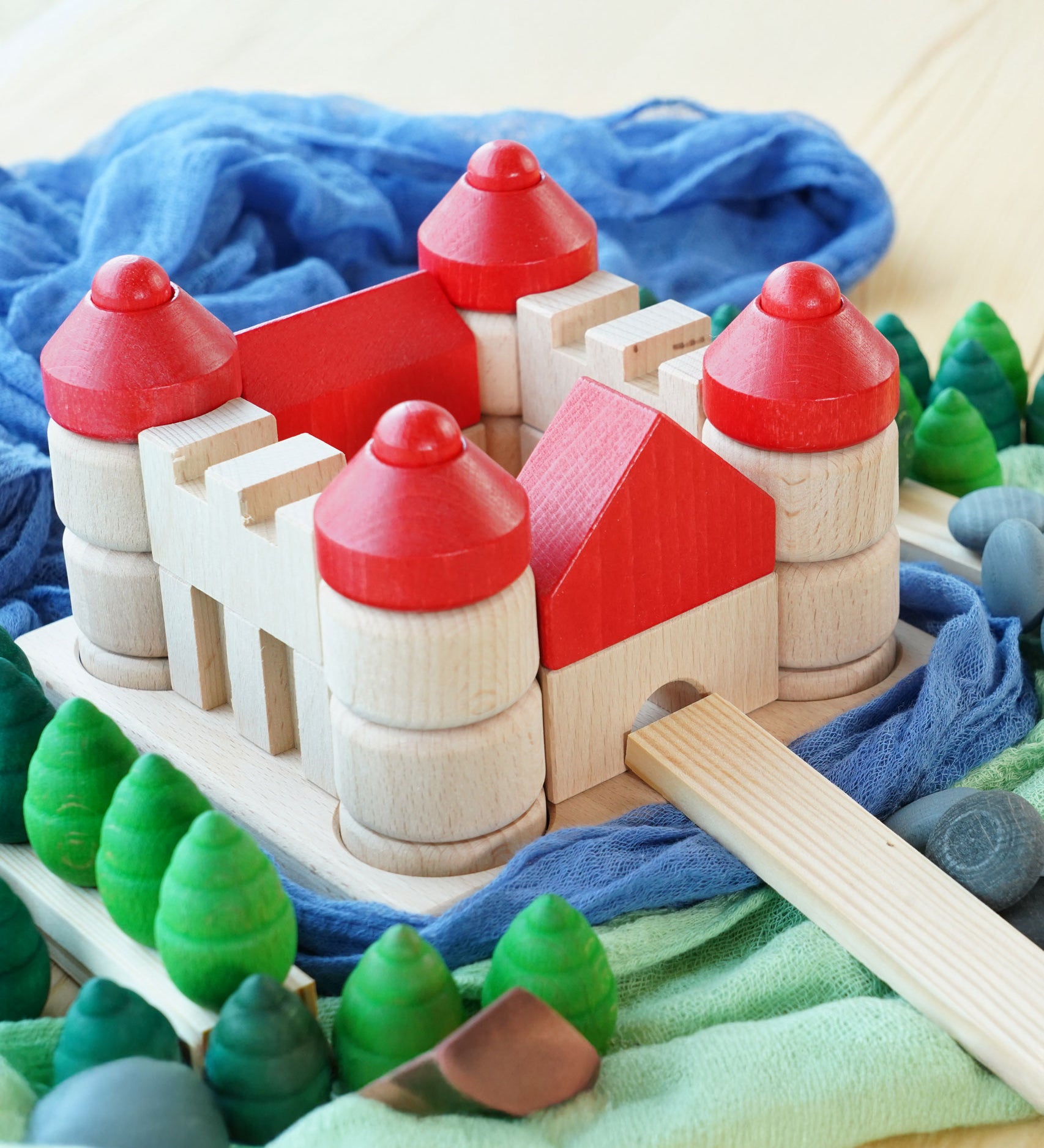 The Bajo Wooden Castle Stacker Toy shown in a small world play set up with Grapat mandala pieces and Ostheimer cloths.