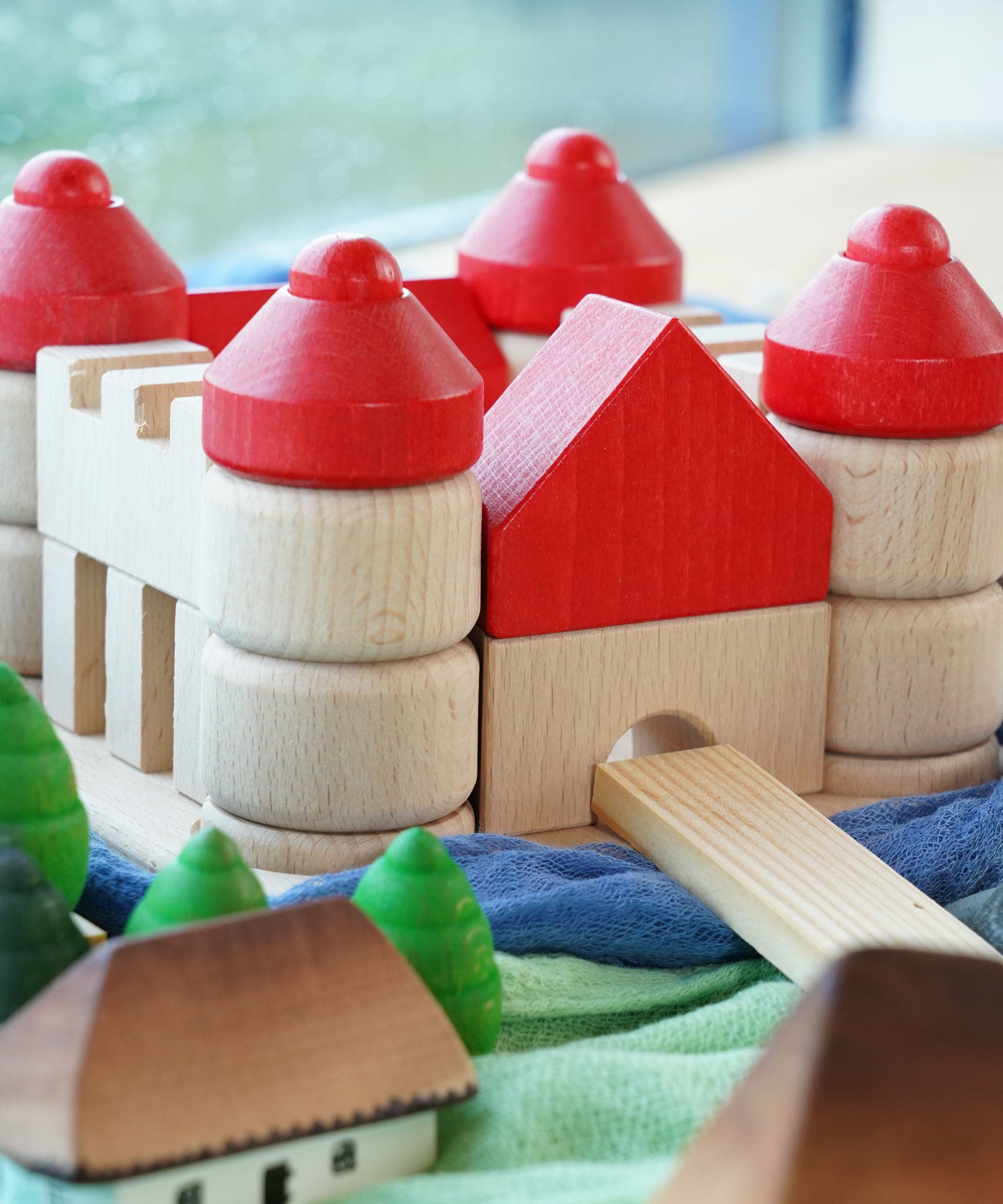 The Bajo Wooden Castle Stacker Toy shown in a small world play set up with Grapat mandala pieces and Ostheimer cloths.
