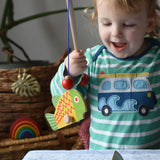 Bajo magnetic fishing game toy. Child holding wooden rod with yellow and green fish attached.