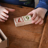 A child taking placing two number blocks 6 and 7 next to each other from the box of Bajo 40 Numbers & Symbols Blocks set. These heirloom quality toys by Bajo are part of a wide range of wooden toys available here at Babipur. 