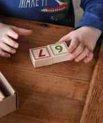 A child taking placing two number blocks 6 and 7 next to each other from the box of Bajo 40 Numbers & Symbols Blocks set. These heirloom quality toys by Bajo are part of a wide range of wooden toys available here at Babipur. 