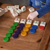 A child playing the blocks from the Bajo 40 Numbers & Symbols Blocks set. The 1 to 5 number blocks have been lined up with the corresponding number of Grapat wooden coins placed next to them. These heirloom quality toys by Bajo are part of a wide range of wooden toys available here at Babipur. 