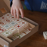 A child reaching for the blocks from the box of Bajo 40 Numbers & Symbols Blocks set. These heirloom quality toys by Bajo are part of a wide range of wooden toys available here at Babipur. 